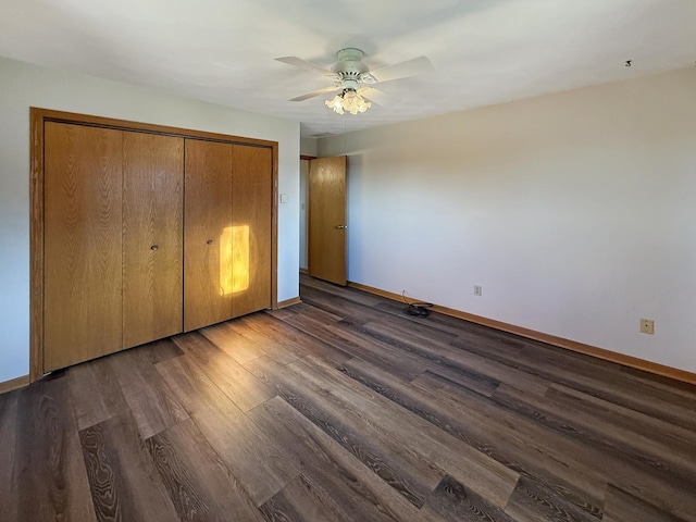 unfurnished bedroom featuring ceiling fan, baseboards, dark wood-type flooring, and a closet
