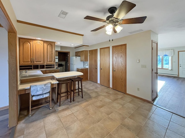 kitchen featuring a peninsula, visible vents, baseboards, freestanding refrigerator, and ceiling fan