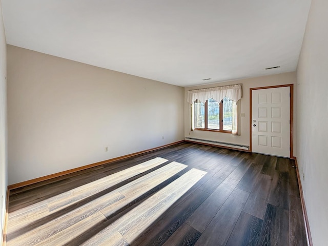 empty room with a baseboard heating unit, baseboards, dark wood-style floors, and visible vents