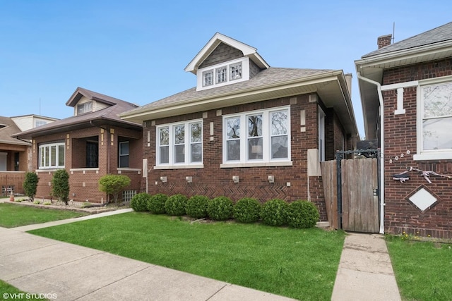 bungalow-style house with a gate, a front lawn, and brick siding