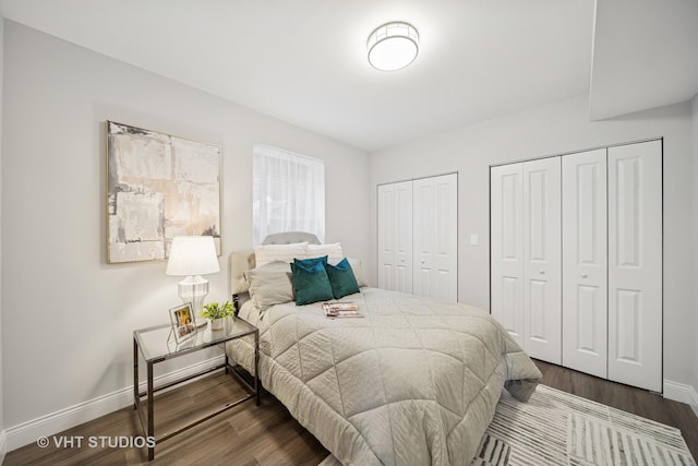 bedroom with baseboards, two closets, and dark wood-style flooring