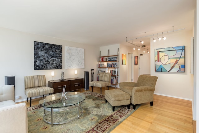 living room with rail lighting, wood finished floors, and baseboards