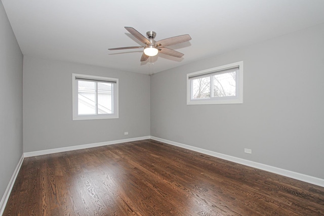 spare room featuring baseboards, dark wood-type flooring, and ceiling fan