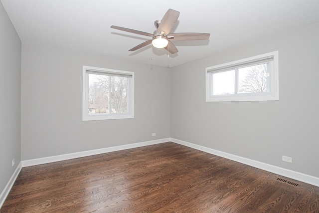 unfurnished room with visible vents, a ceiling fan, baseboards, and dark wood-style flooring