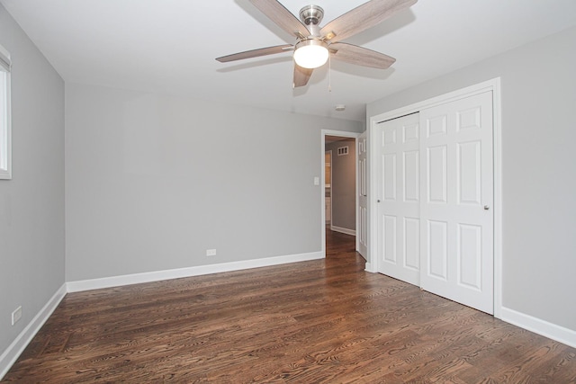 unfurnished bedroom with baseboards, dark wood-style flooring, and a closet