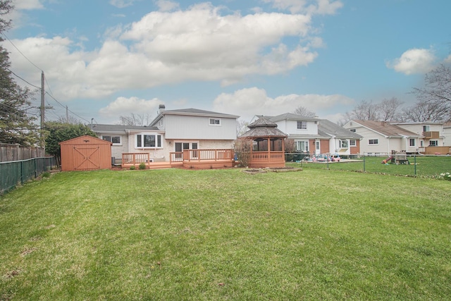 view of yard featuring a gazebo, a shed, a deck, a fenced backyard, and an outbuilding