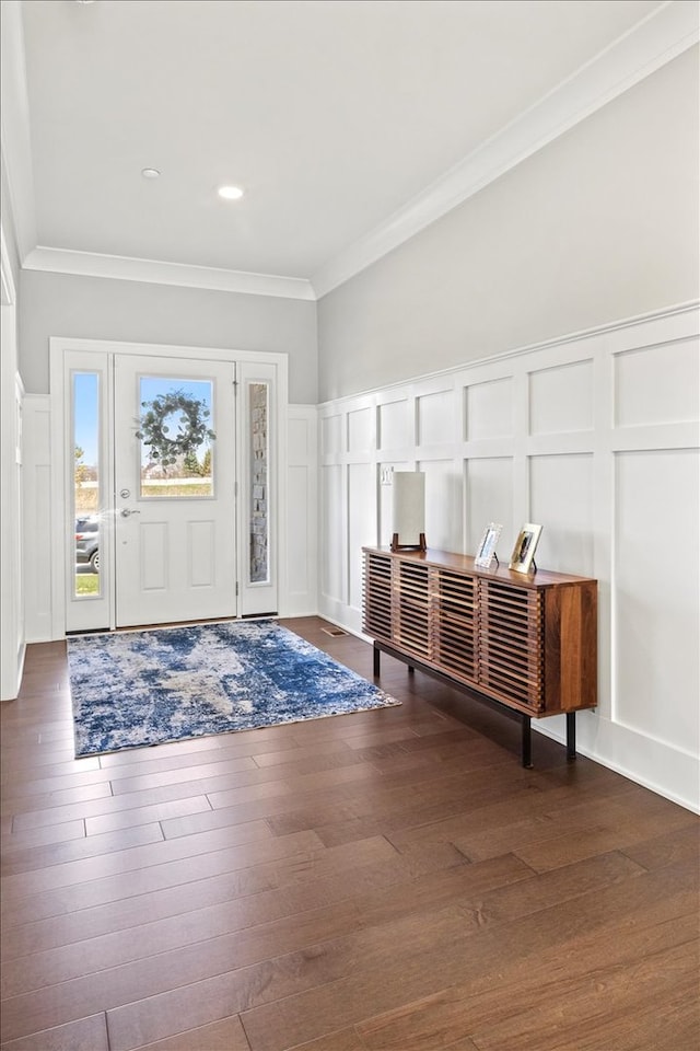 foyer featuring a decorative wall, ornamental molding, and wood finished floors