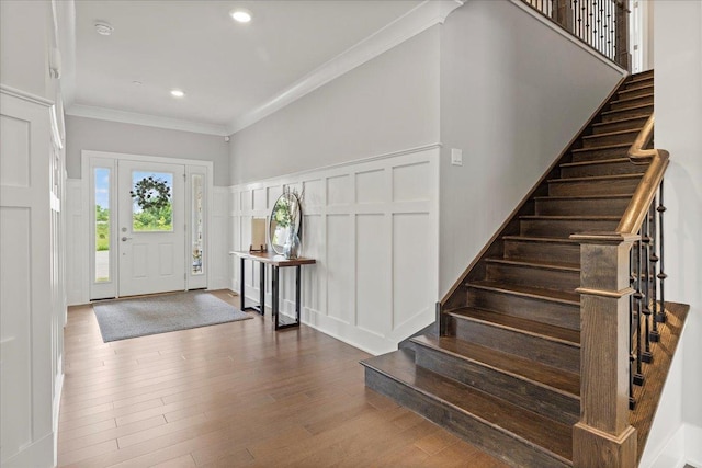 entryway featuring wood finished floors, stairs, ornamental molding, and a decorative wall