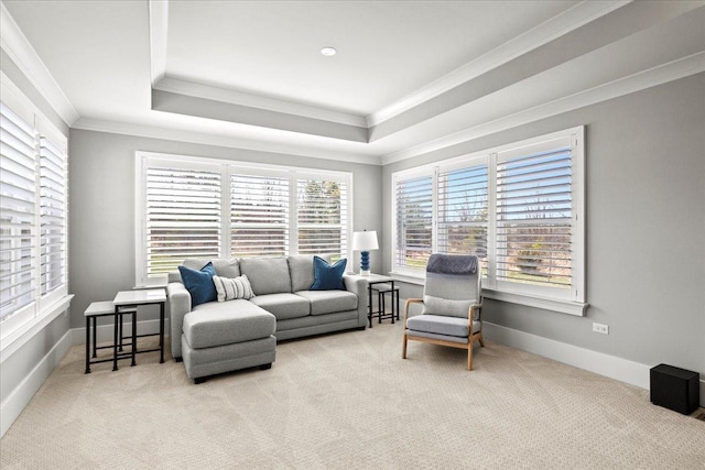 living area with baseboards, crown molding, a tray ceiling, and carpet