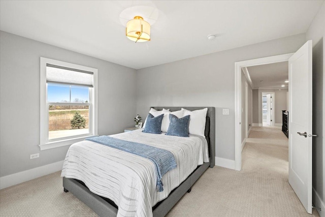 bedroom with baseboards and light colored carpet
