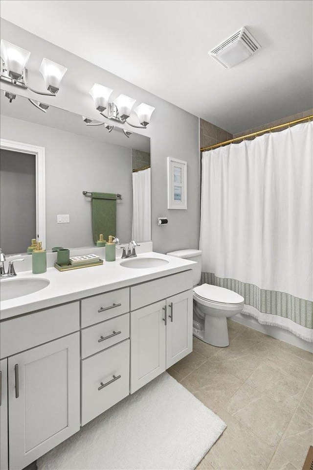 bathroom with double vanity, visible vents, toilet, and a sink