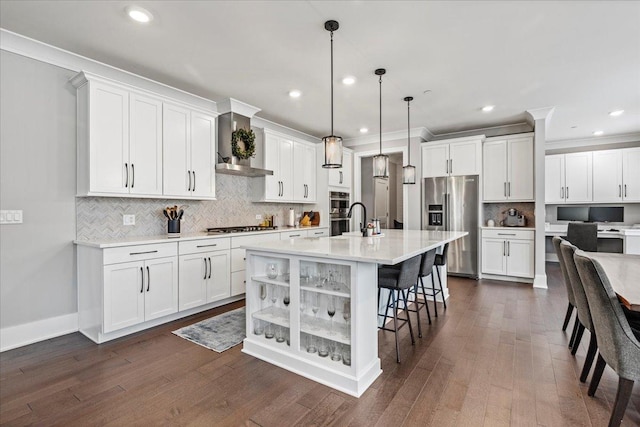 kitchen featuring backsplash, wall chimney range hood, appliances with stainless steel finishes, and white cabinetry