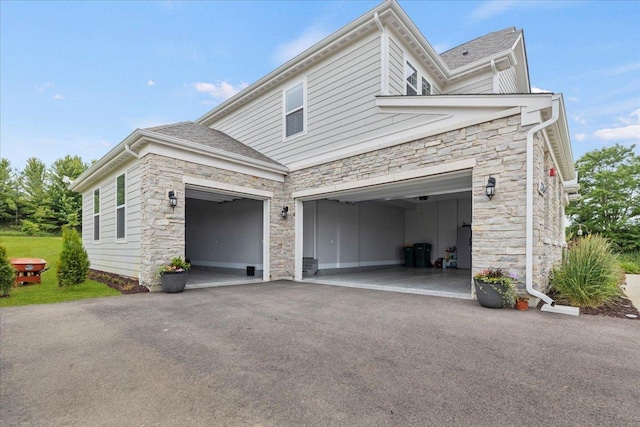 view of side of property featuring a garage, driveway, and stone siding
