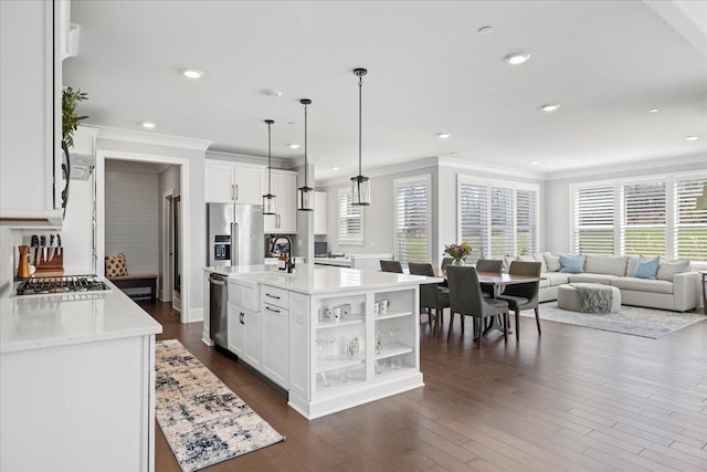 kitchen with open floor plan, appliances with stainless steel finishes, ornamental molding, and a healthy amount of sunlight