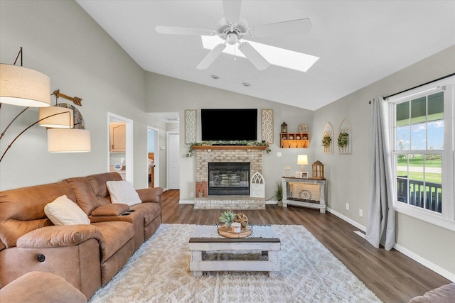 living room featuring wood finished floors, a skylight, ceiling fan, a fireplace, and baseboards