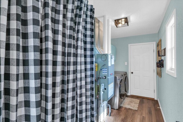 laundry room featuring washing machine and clothes dryer, dark wood-style flooring, laundry area, and baseboards