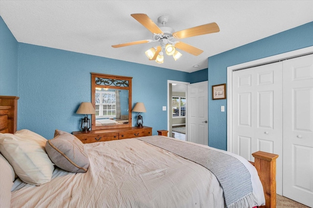 bedroom with a textured wall, a closet, carpet flooring, and ceiling fan