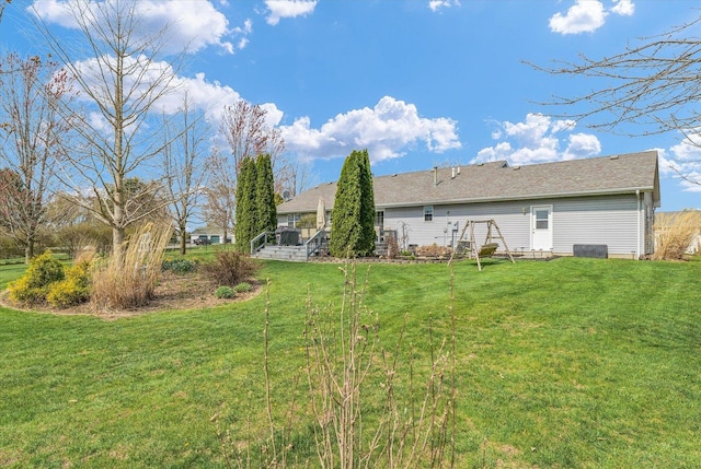rear view of property with a lawn and a shingled roof