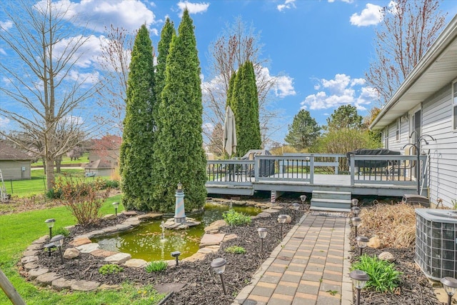 view of yard featuring a garden pond, a wooden deck, and central air condition unit