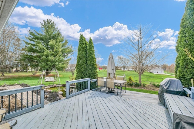 wooden terrace with outdoor dining area, a grill, and a yard