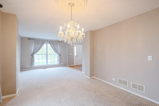unfurnished room with an inviting chandelier, visible vents, light colored carpet, and baseboards