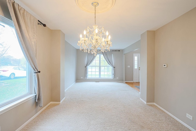 unfurnished dining area with light carpet, a chandelier, and baseboards