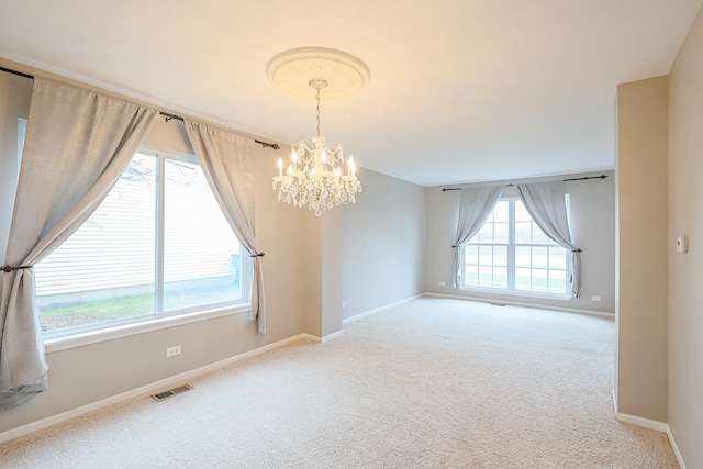 empty room with visible vents, baseboards, a chandelier, and carpet floors