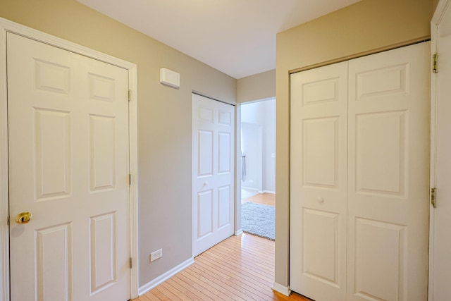 unfurnished bedroom featuring light wood finished floors, a closet, and baseboards