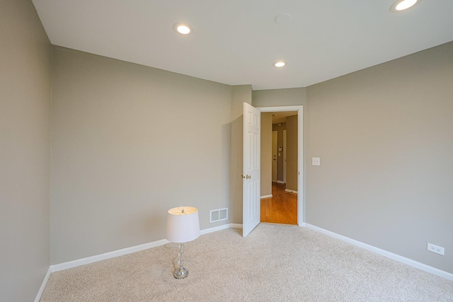 empty room featuring baseboards, visible vents, light colored carpet, and recessed lighting