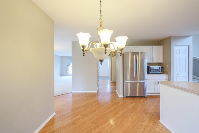 kitchen with white cabinetry, light wood-type flooring, stainless steel appliances, and an inviting chandelier