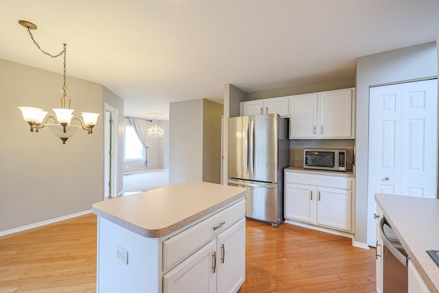 kitchen featuring a chandelier, stainless steel appliances, light wood-type flooring, and light countertops