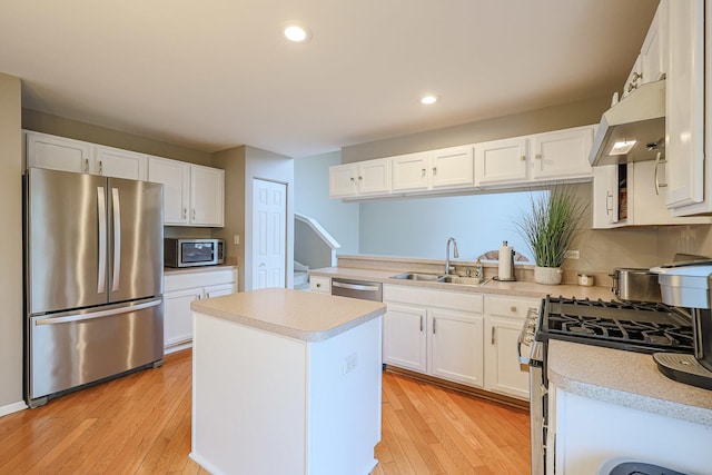 kitchen with white cabinets, a sink, appliances with stainless steel finishes, light countertops, and under cabinet range hood