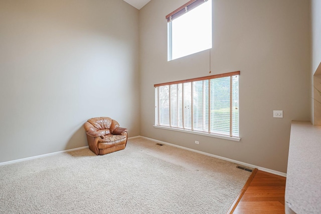 sitting room featuring a high ceiling, baseboards, and a healthy amount of sunlight