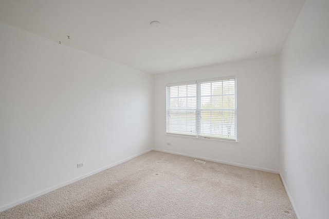 empty room with visible vents, baseboards, and light carpet