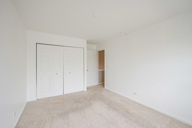 unfurnished bedroom with a closet, baseboards, and carpet floors