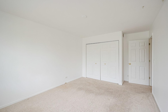 unfurnished bedroom with carpet, baseboards, and a closet