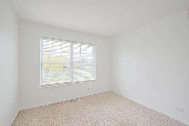 empty room featuring carpet, visible vents, and baseboards