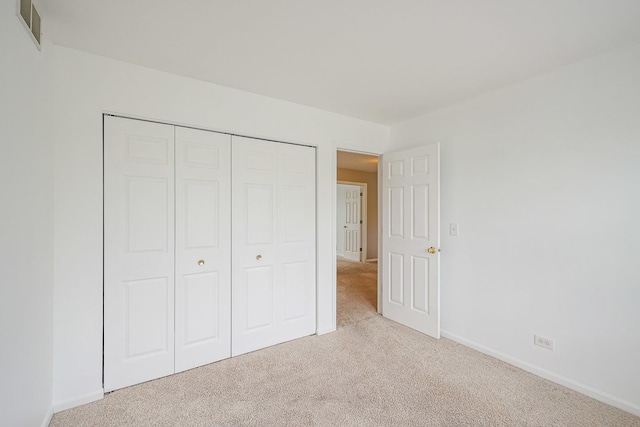 unfurnished bedroom featuring carpet, visible vents, a closet, and baseboards