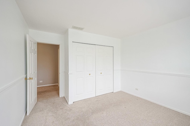 unfurnished bedroom featuring a closet, visible vents, light colored carpet, and baseboards