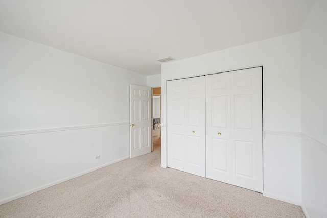 unfurnished bedroom featuring carpet, visible vents, baseboards, and a closet