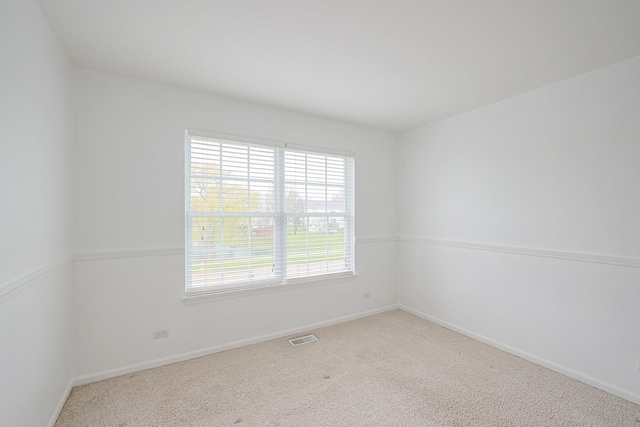 carpeted empty room featuring baseboards and visible vents
