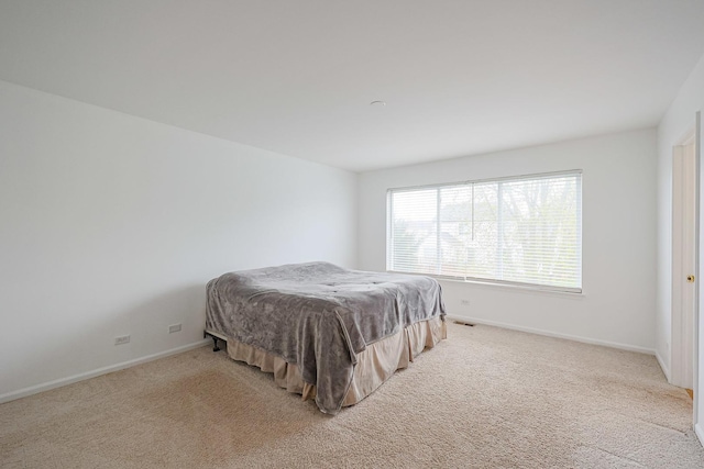 bedroom featuring visible vents, light carpet, and baseboards