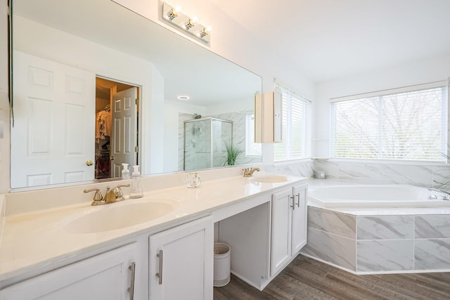 bathroom with a stall shower, wood finished floors, double vanity, and a sink