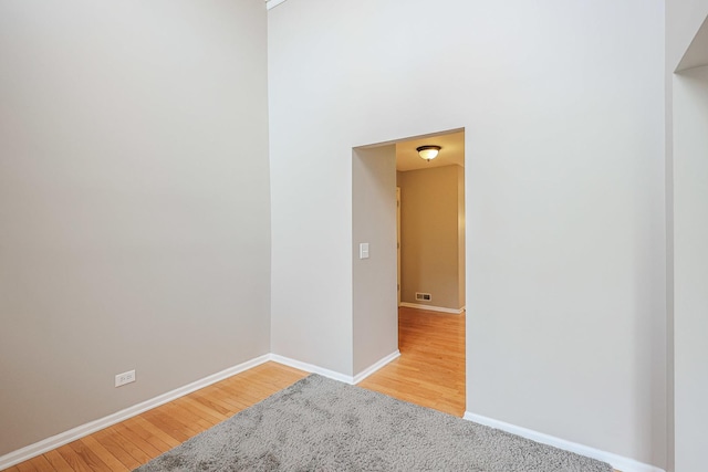 spare room with baseboards, visible vents, and wood finished floors