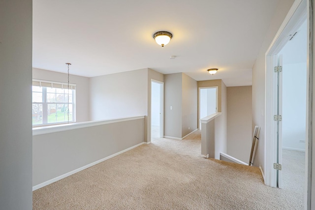 spare room with baseboards, an inviting chandelier, and carpet