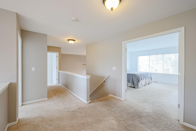 hall with an upstairs landing, carpet floors, and baseboards