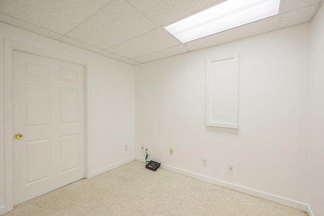 unfurnished room with a paneled ceiling, carpet flooring, and baseboards