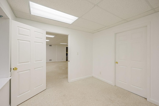 spare room with light colored carpet, a drop ceiling, and baseboards