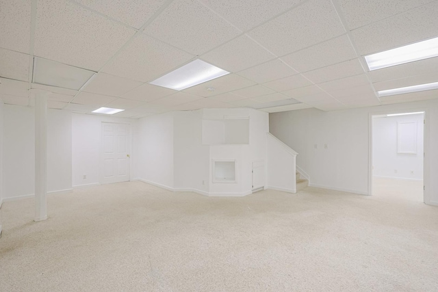 finished basement featuring stairs, carpet flooring, a drop ceiling, and baseboards