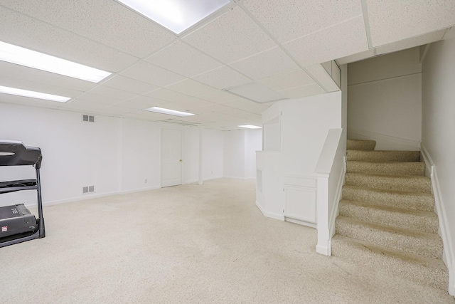 finished below grade area featuring visible vents, light carpet, and stairway